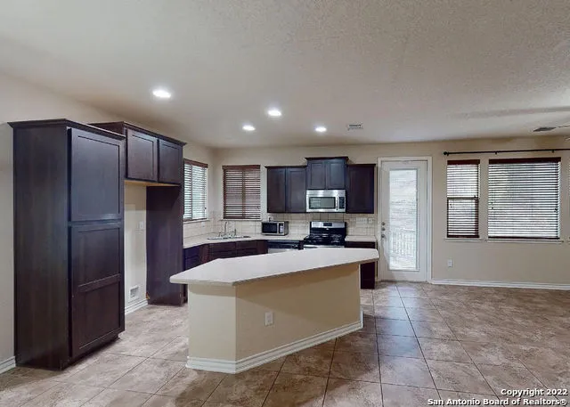a large kitchen with stainless steel appliances kitchen island granite countertop a refrigerator and a stove top oven
