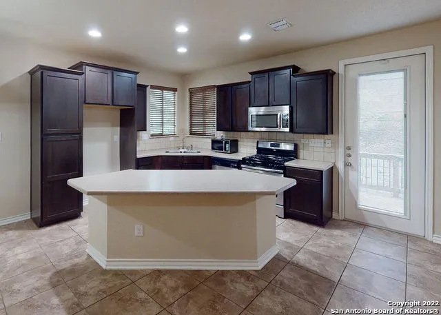 a kitchen with kitchen island granite countertop wooden cabinets a refrigerator and a sink