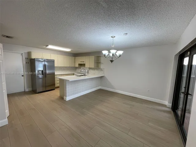 an empty room with wooden floor and stainless steel appliances