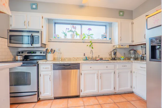 a kitchen with stainless steel appliances granite countertop a stove a sink and a microwave