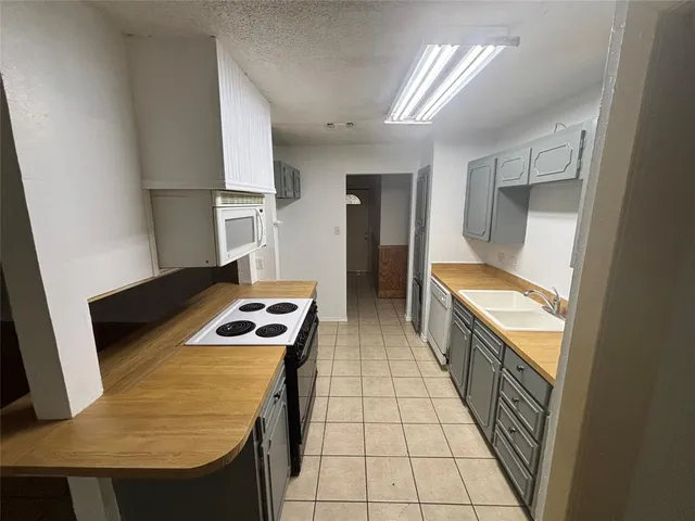 a kitchen with granite countertop a sink a stove and a refrigerator