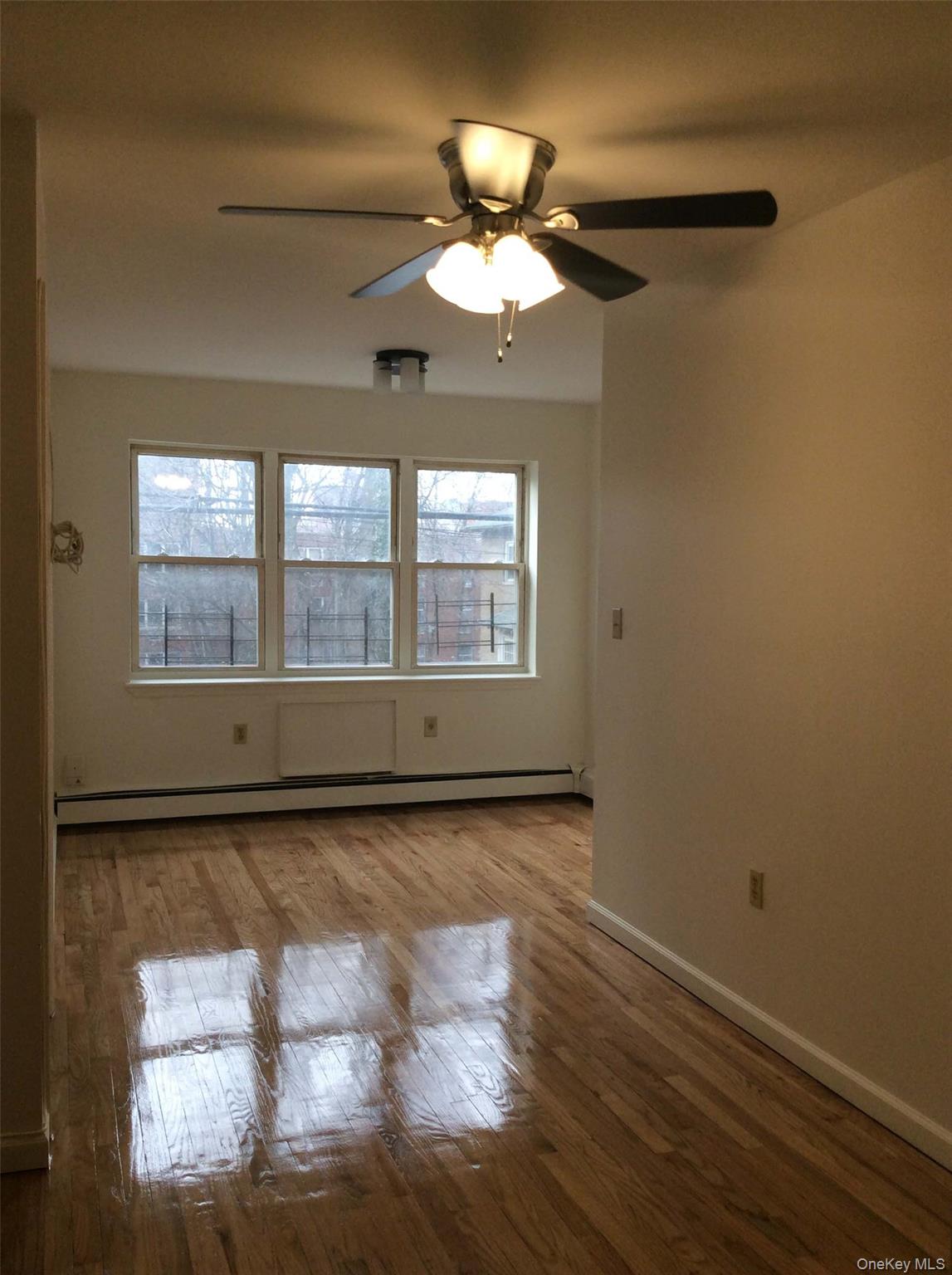 Spare room with light wood-style flooring, baseboard heating, and a ceiling fan