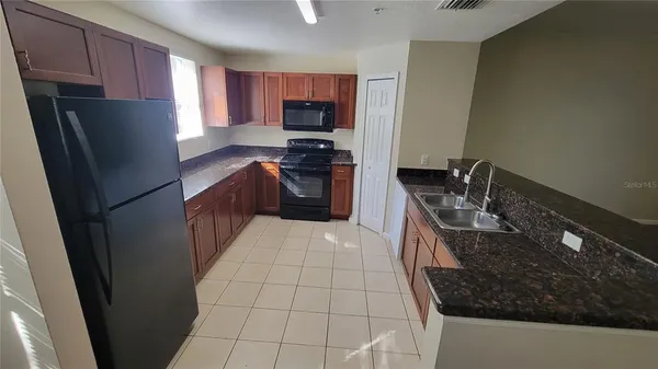 a kitchen with granite countertop a refrigerator stove and sink