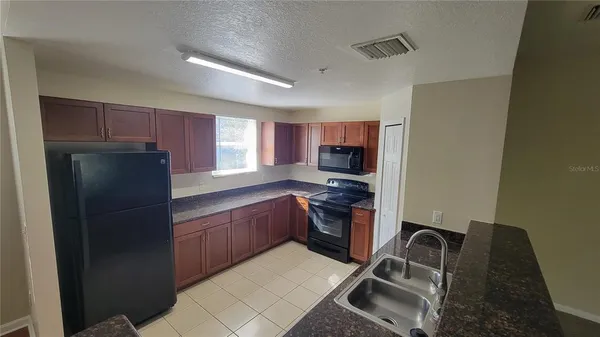 a kitchen with granite countertop a refrigerator stove and sink