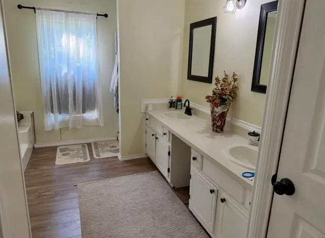 a bathroom with a double vanity sink a mirror and a bathtub
