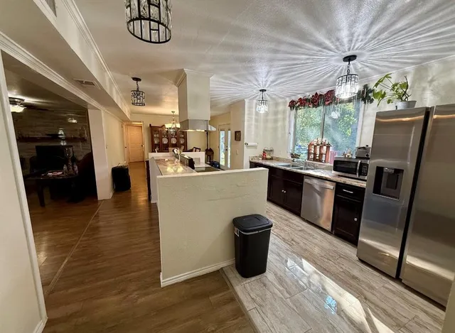 a kitchen with stainless steel appliances granite countertop a refrigerator a sink dishwasher a stove and white countertops with wooden floor