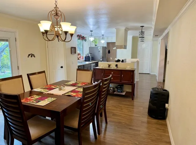 a dining room with wooden floor a chandelier a wooden table and chairs