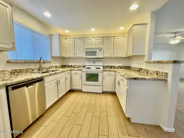 a kitchen with a white cabinets a sink dishwasher and a stove with wooden floor