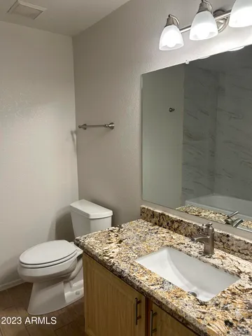 a bathroom with a granite countertop sink a toilet and a mirror