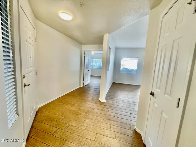 a view of a hallway with wooden floor and a bathroom