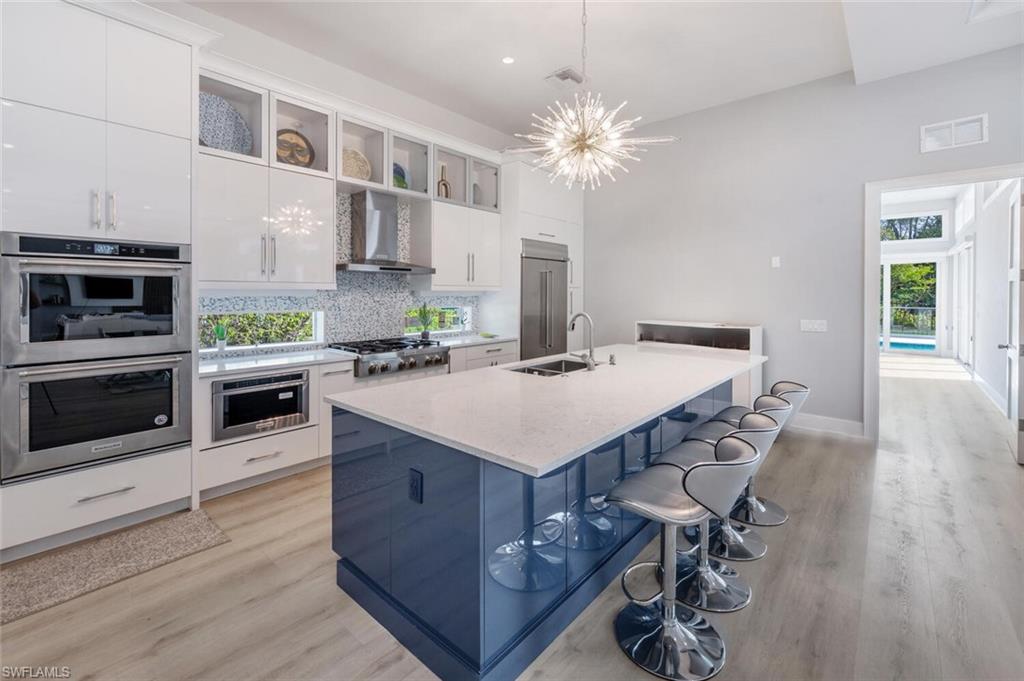 9240 The Lane Naples, FL 34109 - Photo 15 of 42 a kitchen with a table chairs stainless steel appliances and wooden floor