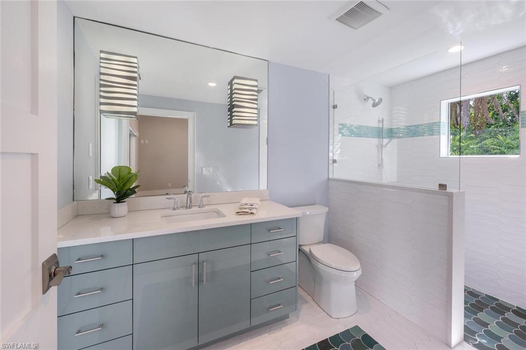 9240 The Lane Naples, FL 34109 - Photo 22 of 42 a bathroom with a granite countertop sink a toilet and mirror