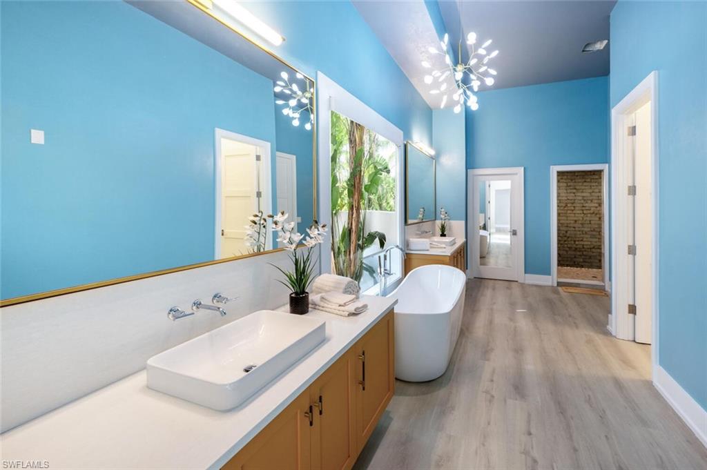 9240 The Lane Naples, FL 34109 - Photo 23 of 42 a spacious bathroom with a granite countertop sink a large mirror and shower