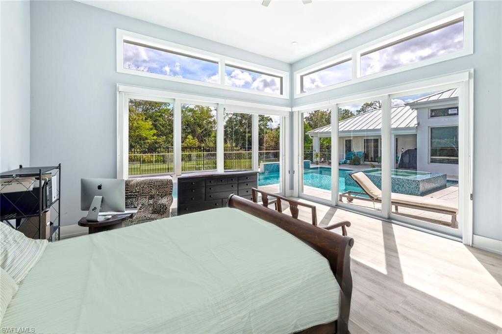 9240 The Lane Naples, FL 34109 - Photo 38 of 42 a bedroom with a bed and a large window with balcony view
