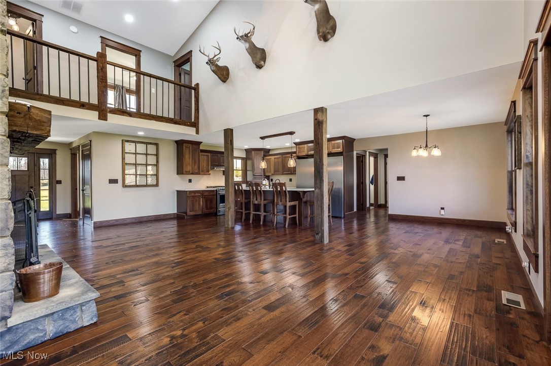 9615 Rural Dale Road Blue Rock, OH 43720 - Photo 25 of 50 Unfurnished living room featuring dark wood-style floors, a towering ceiling, a chandelier, and recessed lighting
