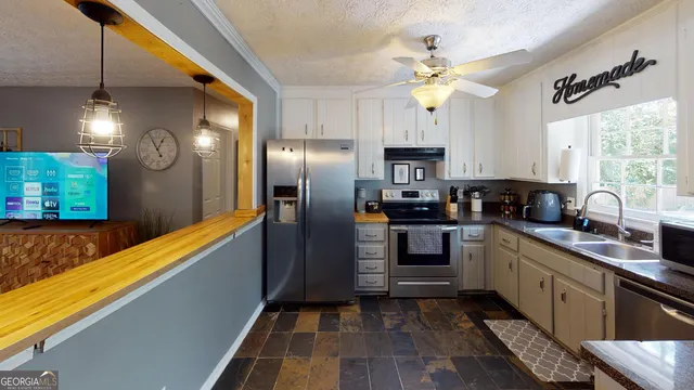 a kitchen with stainless steel appliances granite countertop a refrigerator a sink dishwasher a stove and white countertops with wooden floor