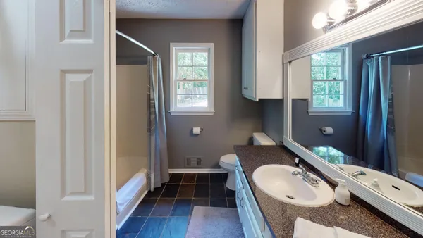 a en suite bathroom with a granite countertop double vanity sink a mirror and a window