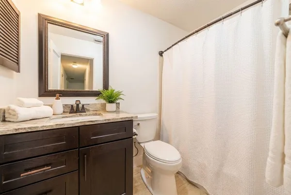 a bathroom with a granite countertop sink and a mirror with toilet