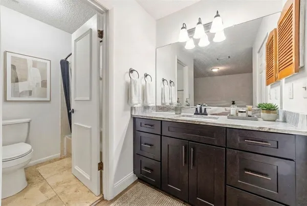 a bathroom with a granite countertop sink toilet and shower
