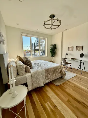 a bedroom with a bed a chandelier and a potted plant on the dresser