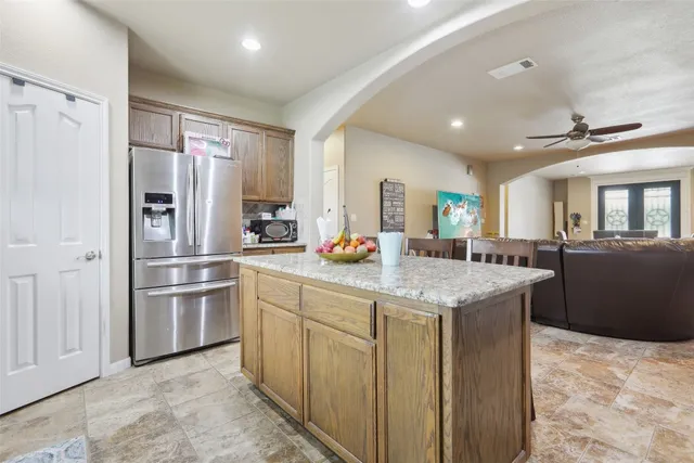 a kitchen with stainless steel appliances granite countertop a refrigerator a sink dishwasher and a stove with wooden floor