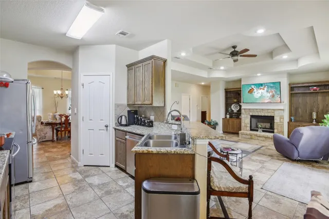 a living room with furniture a fireplace and a open kitchen view