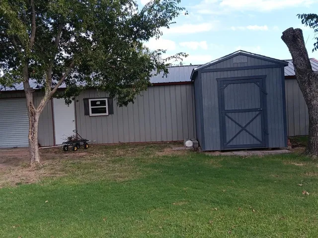 a view of a backyard with a barn and a large tree