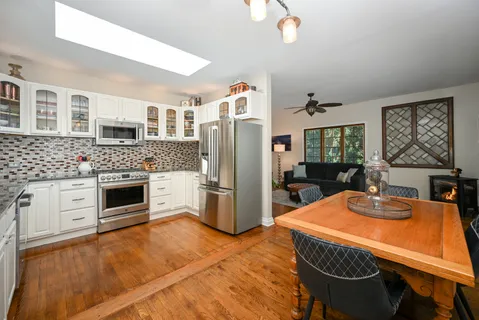a kitchen with stainless steel appliances white cabinets and wooden floor
