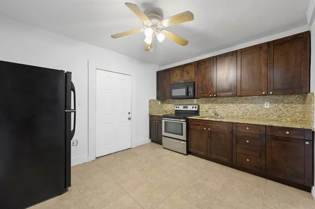 a kitchen with granite countertop wooden cabinets a refrigerator a stove a sink and dishwasher