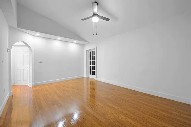 a view of an empty room with wooden floor fridge and a window