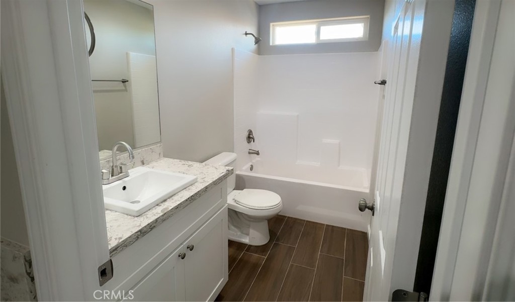 16506 Cactus Street Hesperia, CA 92345 - Photo 28 of 34 a bathroom with a granite countertop toilet a sink and a mirror