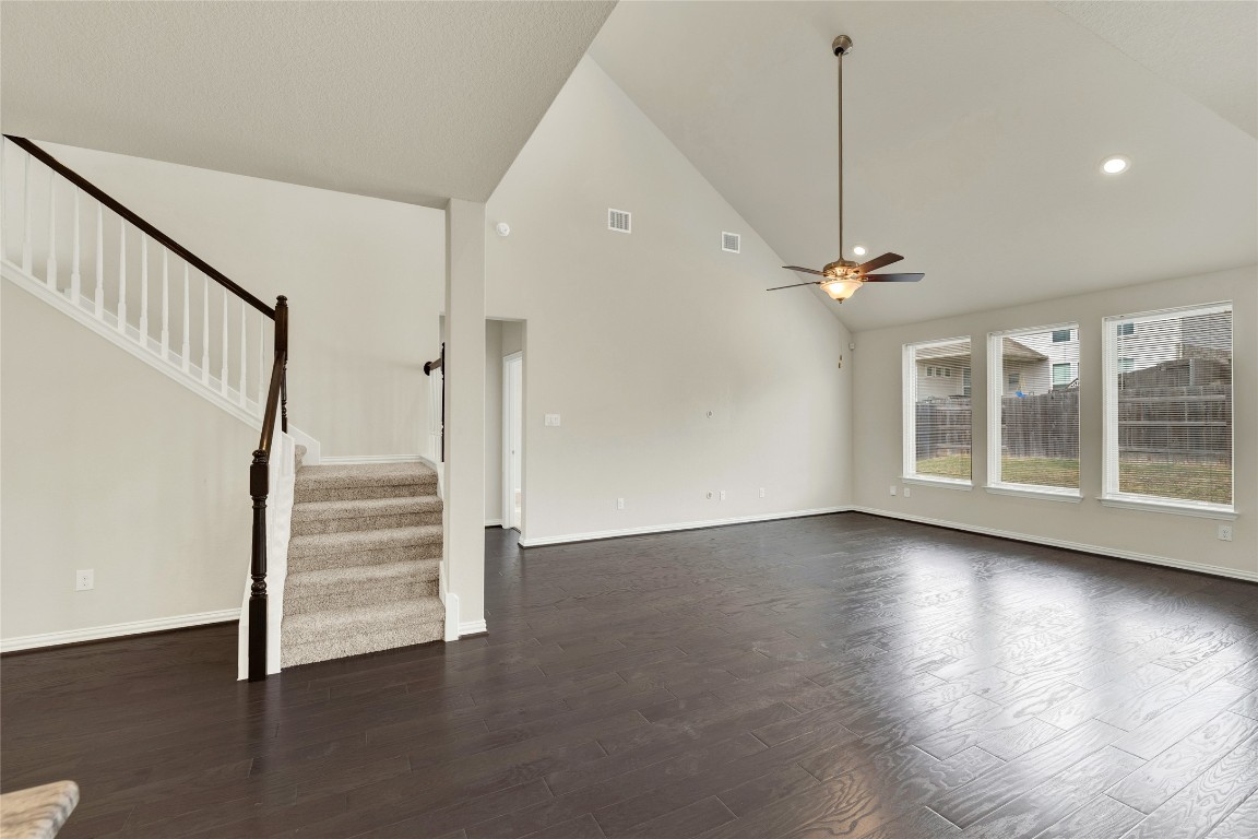 908 Leadtree Loop Buda, TX 78610 - Photo 12 of 38 a view of an empty room with wooden floor staircase and a kitchen view
