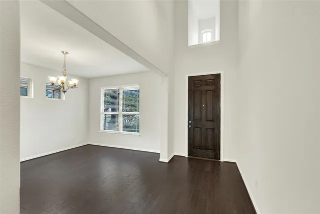 an empty room with wooden floor cabinet and windows
