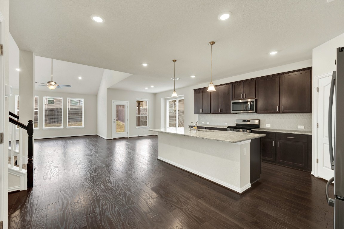 908 Leadtree Loop Buda, TX 78610 - Photo 5 of 38 a kitchen with stainless steel appliances granite countertop a sink dishwasher a refrigerator and a stove with wooden floor