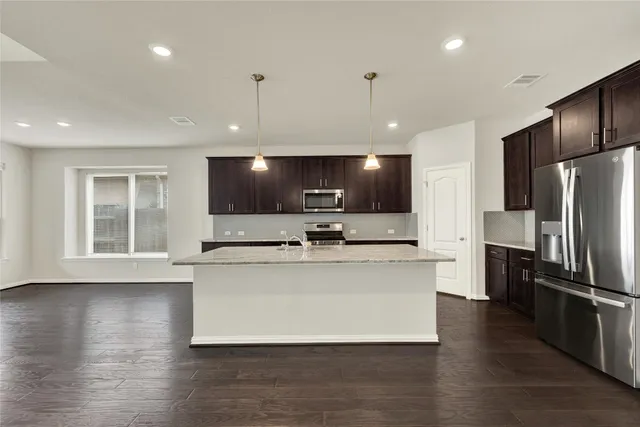 a large kitchen with stainless steel appliances kitchen island a large counter top and a refrigerator