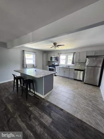 a kitchen with stainless steel appliances granite countertop a table chairs in it and wooden floors