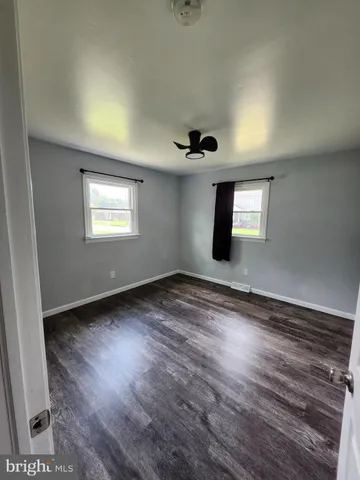 a view of an empty room with window and wooden floor