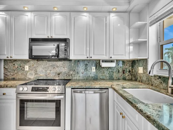 a kitchen with stainless steel appliances granite countertop a stove a refrigerator and a white cabinets