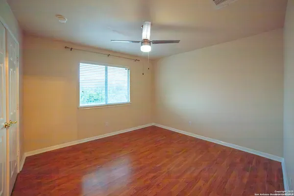 an empty room with wooden floor ceiling fan and windows