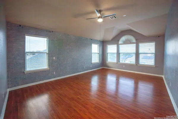 a view of empty room with wooden floor and fan