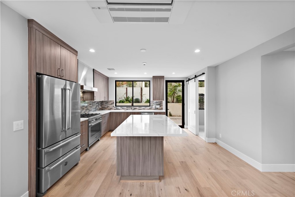 33903 Robles Drive Dana Point, CA 92629 - Photo 13 of 58 a large kitchen with a center island stainless steel appliances counter space and wooden floor