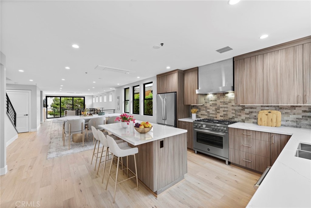 33903 Robles Drive Dana Point, CA 92629 - Photo 15 of 58 a kitchen with stainless steel appliances kitchen island granite countertop a stove a sink a refrigerator and white cabinets with wooden floor