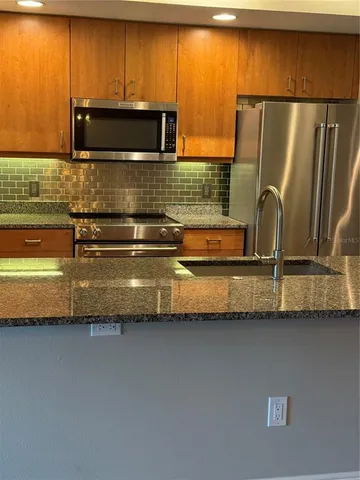 a kitchen with granite countertop a refrigerator and a stove top oven