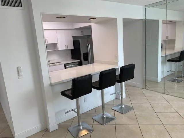 a kitchen with stainless steel appliances kitchen island granite countertop a refrigerator and a sink