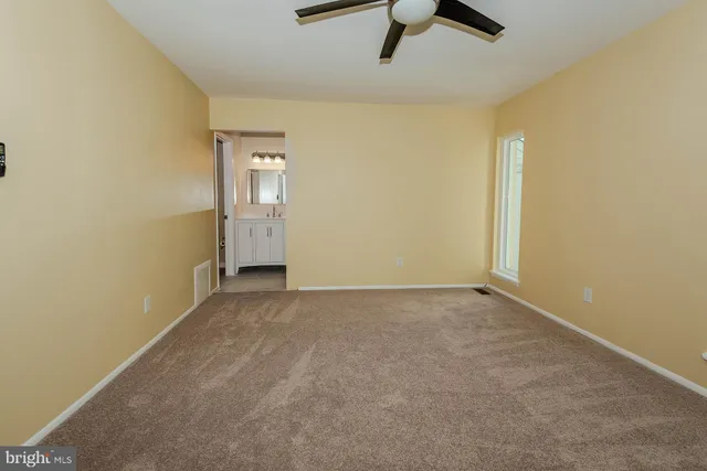 an empty room with ceiling fan and window