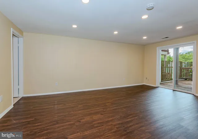 a view of an empty room with wooden floor and windows