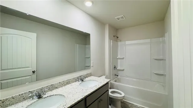 a bathroom with a granite countertop tub sink toilet and a mirror