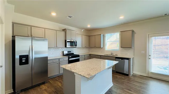 a kitchen with stainless steel appliances granite countertop a refrigerator a sink a stove a microwave and island