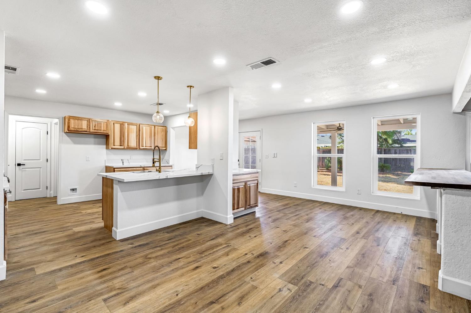 146 Sierra Avenue Clovis, CA 93612 - Photo 18 of 45 a large kitchen with a center island wooden floor stainless steel appliances and windows