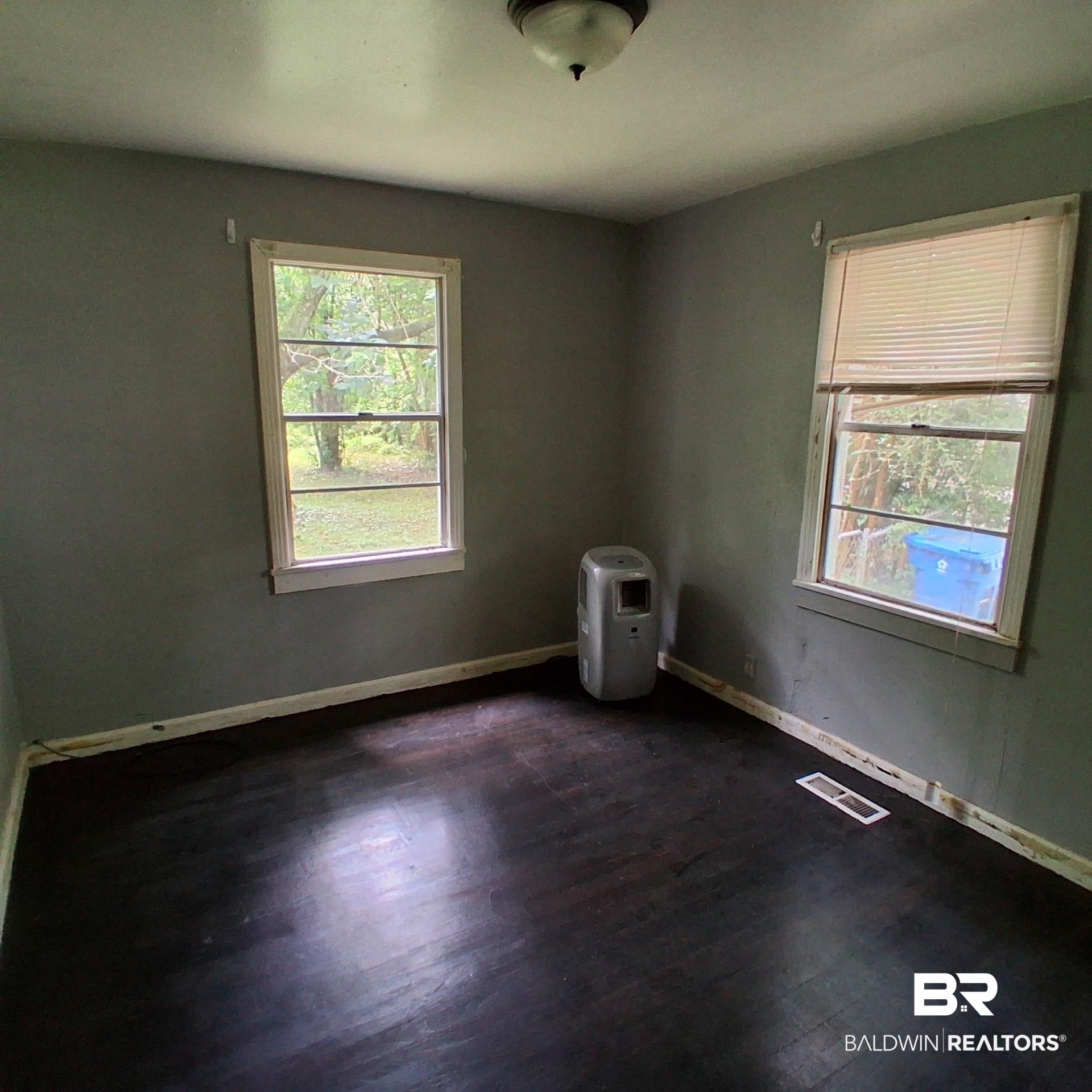 403 Bruner Avenue Evergreen, AL 36401 - Photo 6 of 9 Room featuring dark wood-finish flooring, two window openings, and a ceiling-mounted light fixture